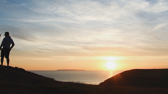 two people on a hill at sunset